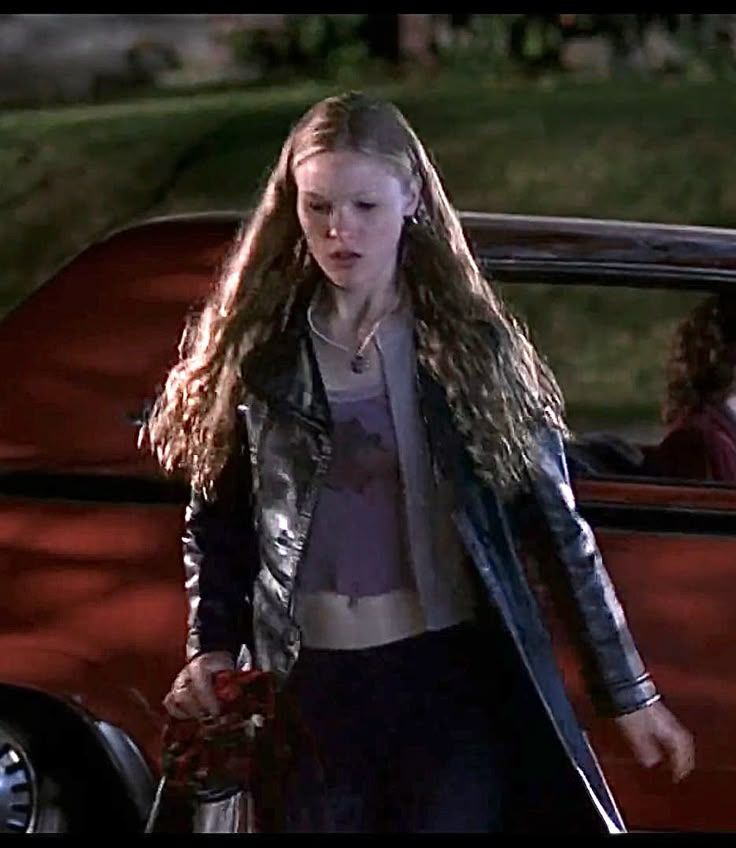 a woman walking next to a red car