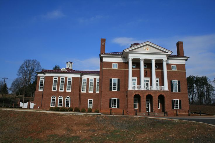 an old brick building with columns and pillars on the front, surrounded by green grass