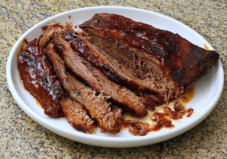 a white plate topped with meat covered in bbq sauce on top of a counter