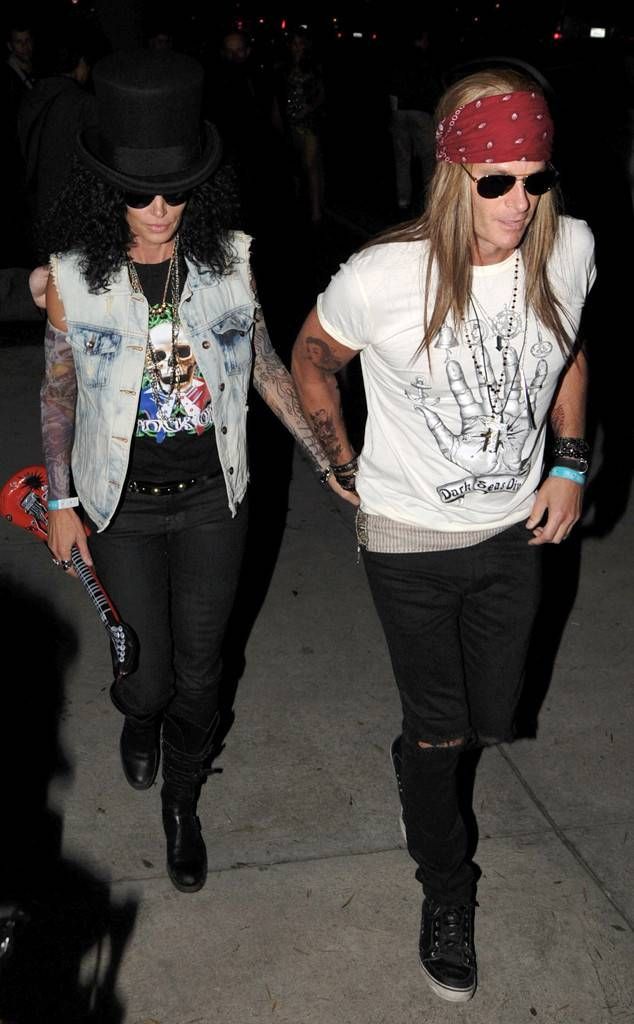 two people walking down the street at night with one person wearing a bandana and another holding a skateboard