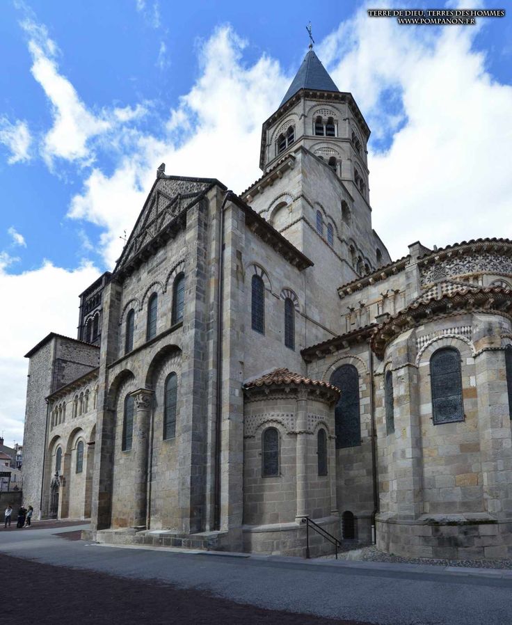 an old stone church with a steeple and clock tower on the front, under a cloudy blue sky