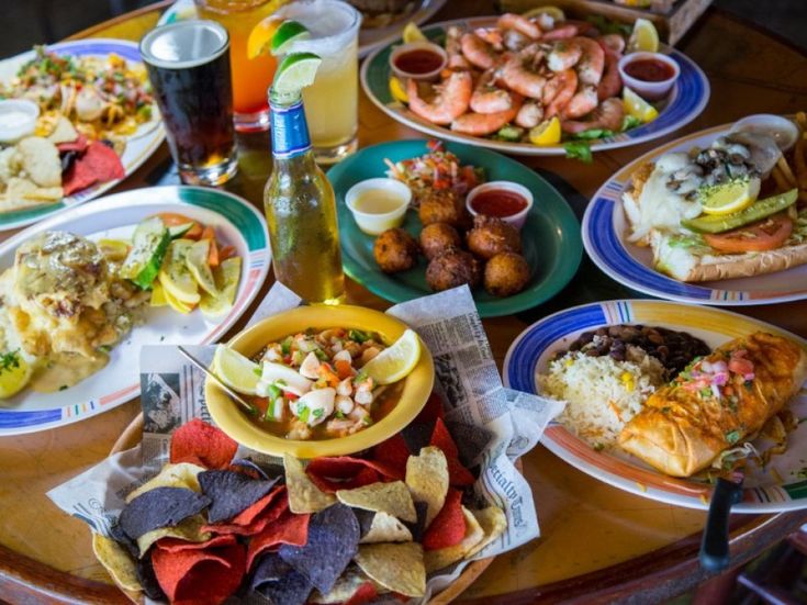 a table full of food and drinks with plates of food on the table in front of them