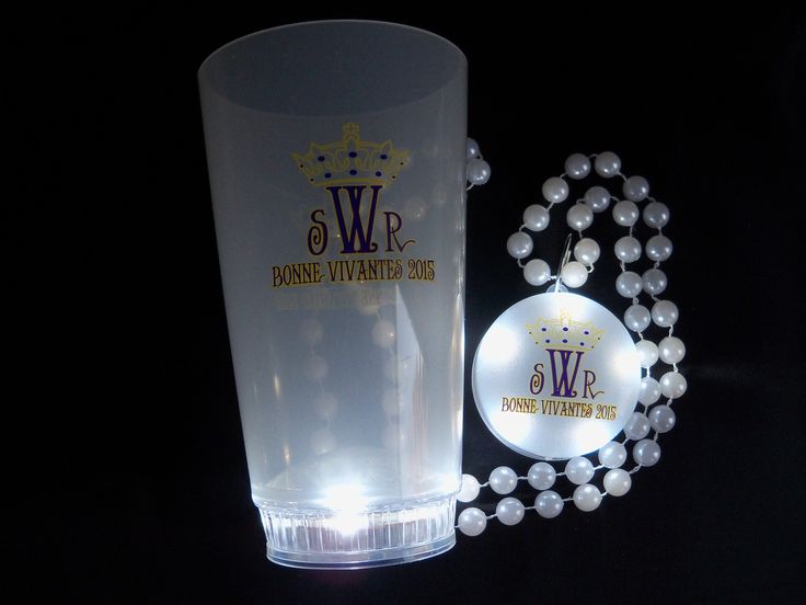 a glass with some beads around it and a light up necklace on the table next to it