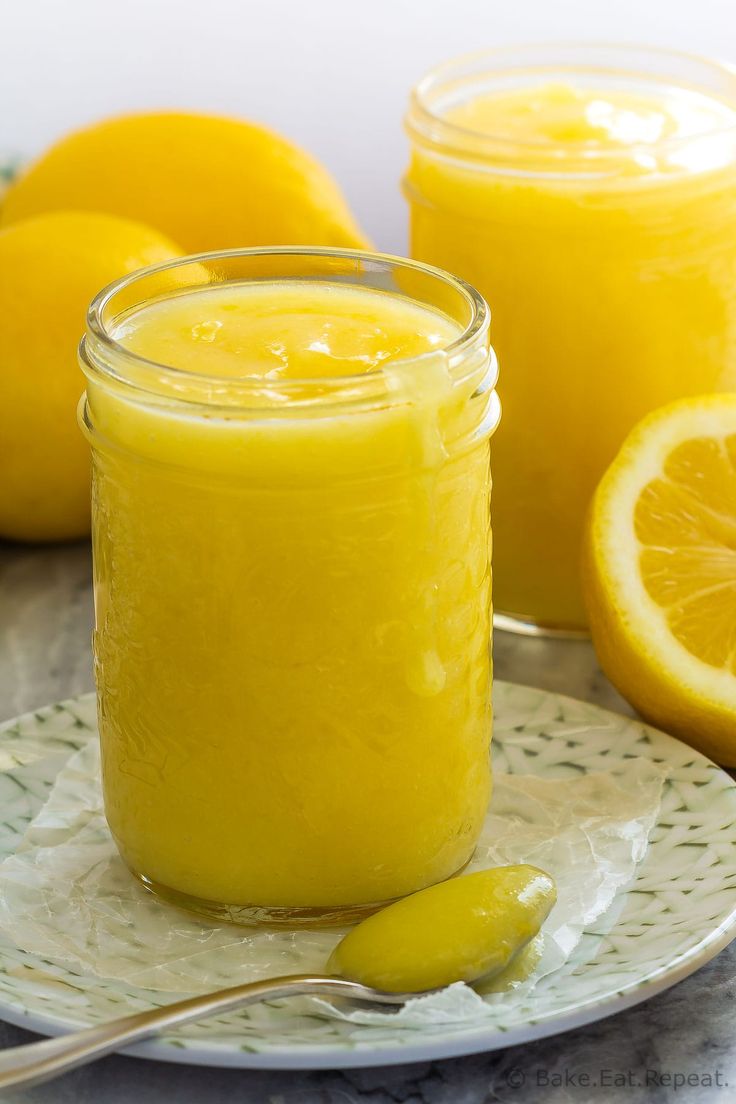 a glass jar filled with yellow liquid next to sliced lemons on a white plate