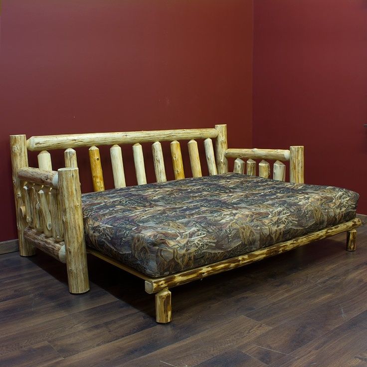 a wooden couch sitting on top of a hard wood floor next to a red wall