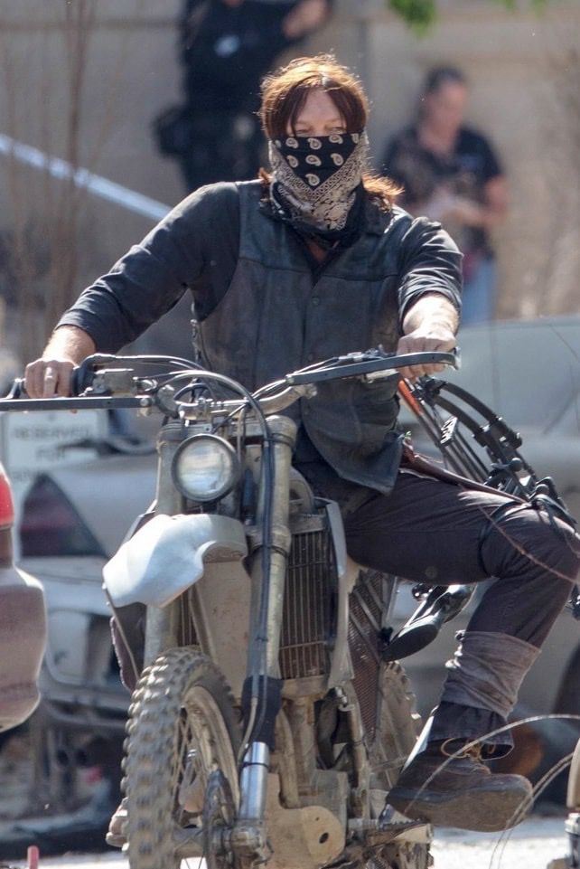 a man riding on the back of a dirt bike wearing a bandana and covering his face