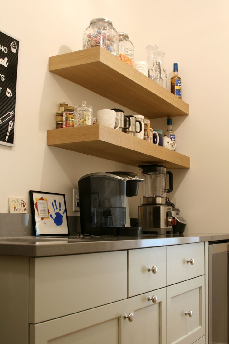 a coffee maker on top of a counter next to shelves filled with cups and other items