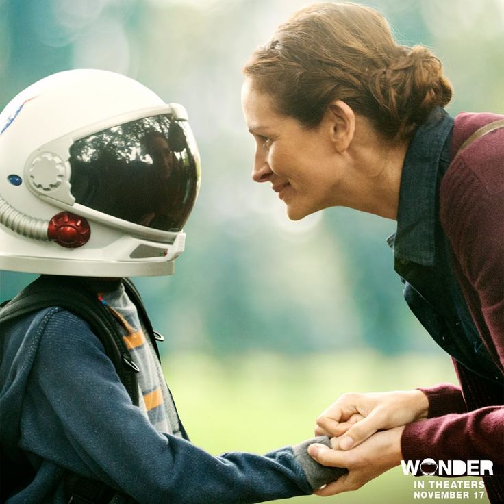 a woman holding the hand of a child wearing a helmet