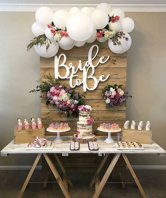 a table topped with cake and balloons next to a wooden sign that says bridal