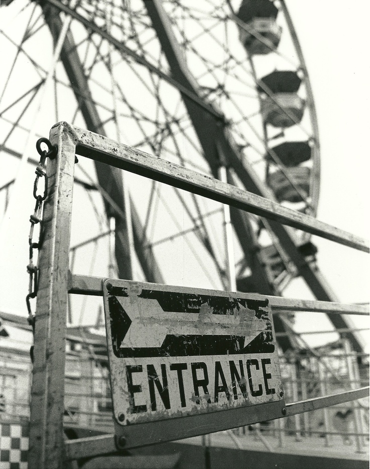 a sign that is next to a ferris wheel with an arrow on the back of it