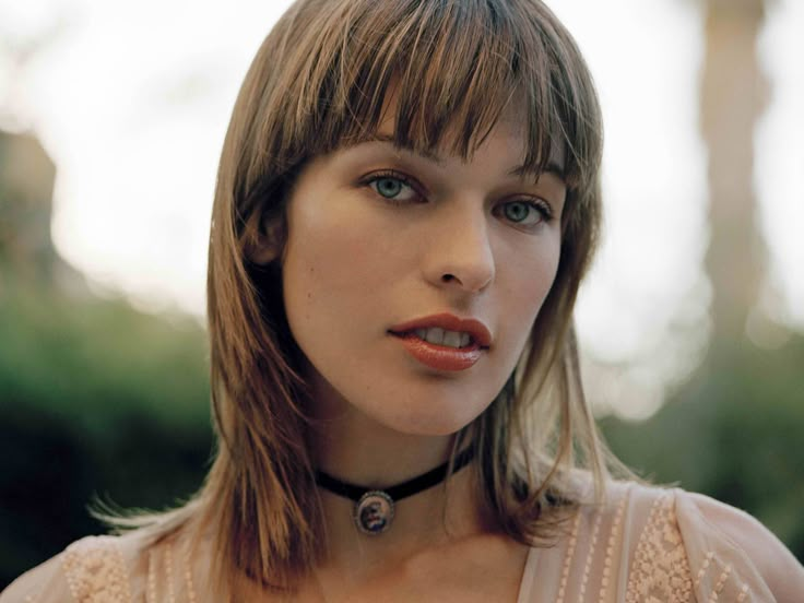 a woman with long hair wearing a collared shirt and looking off to the side