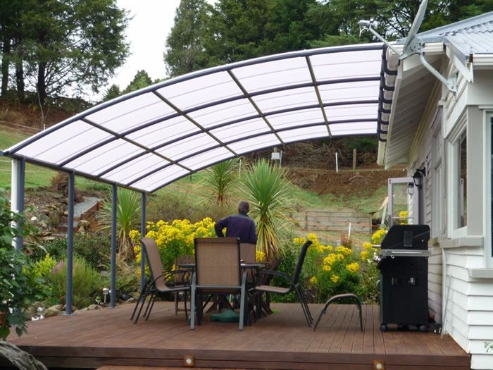 a man sitting at a table on top of a wooden deck under an awning