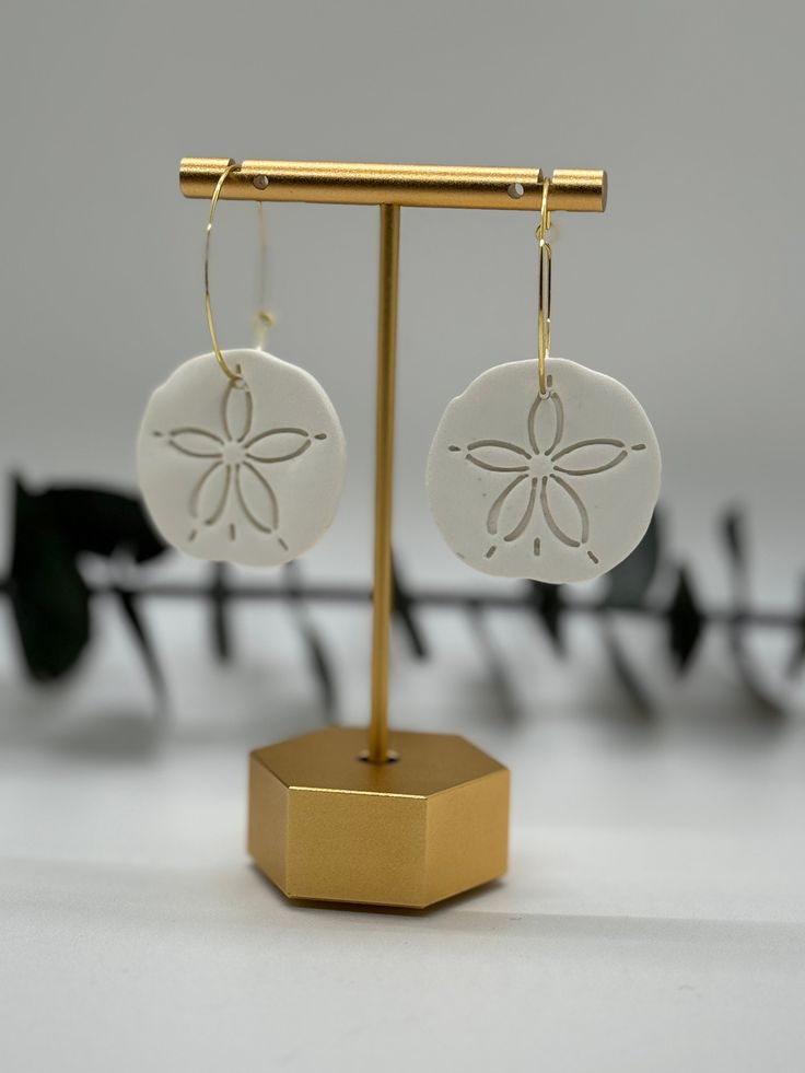 "These Sand Dollar Earrings are lightweight and durable while looking fresh and delicate- the perfect addition to your summer outfit! Bring the beach with you wherever you go! They are made from high quality polymer clay which gives them a durable and lightweight feel.  Size: Sand Dollar- ~1.4\" in diameter 14K Gold Plated Hoop- 1.2\" diameter" White Flower Earrings For Beach, Single Dangle Earring For Beach, Adjustable Drop Flower Earrings For Beach, White Drop Flower Earrings For Beach, White Flower Drop Earrings For Beach, Single Earring For Beach Summer, White Jewelry For Beach Season Gift, Handmade Beachy Earrings For Gift, Handmade Dangle Earrings For Beach Season