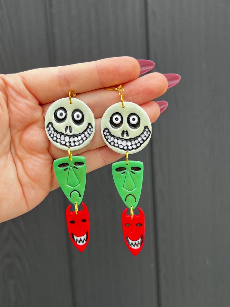 a pair of earrings with faces painted on them are being held in someone's hand