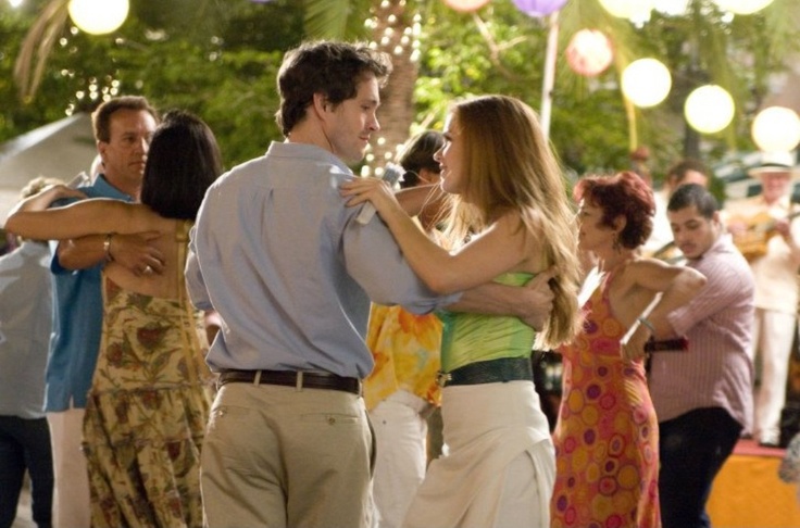 a man and woman dancing together in front of other people at an outdoor dance party