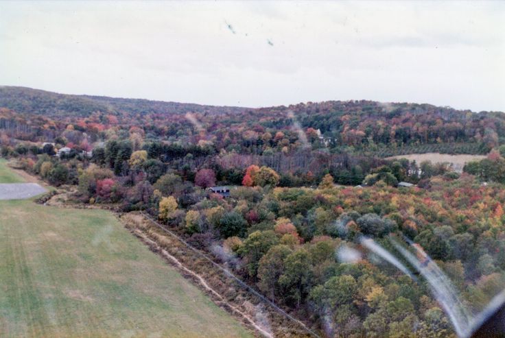 an aerial view of the countryside with trees in fall colors and houses on the other side