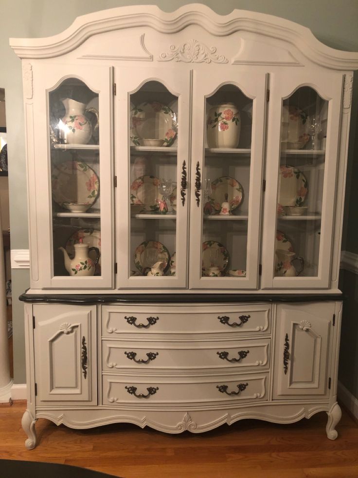 a white china cabinet with glass doors and drawers