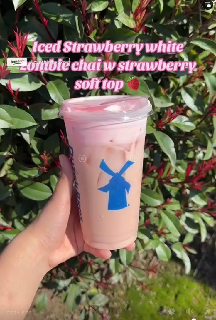 someone is holding up a pink cup with blue designs on it and the words iced strawberry white