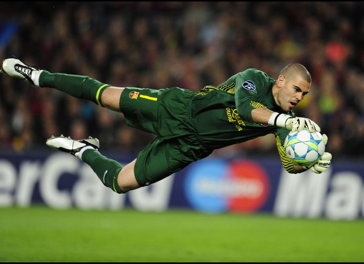 a soccer player in mid air after kicking the ball with his glove and holding it out