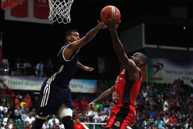 two men playing basketball against each other in front of an audience