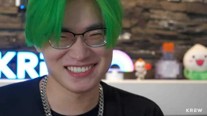 a man with green hair and glasses smiling