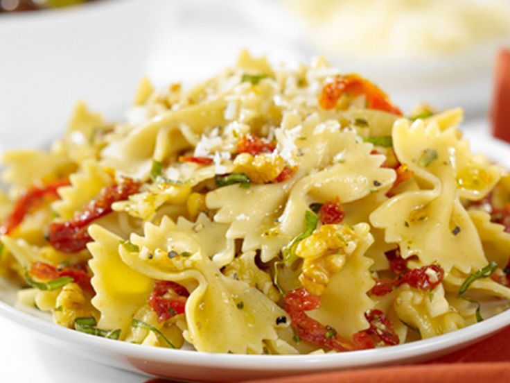 a white bowl filled with pasta and vegetables on top of a red napkin next to other dishes