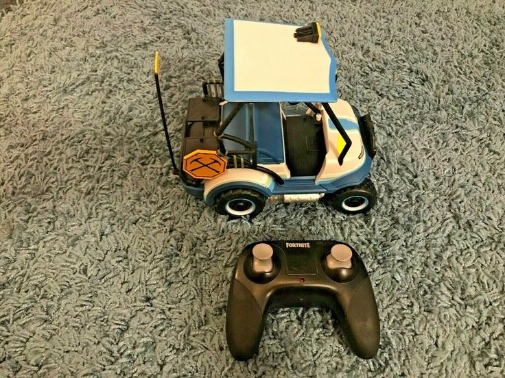 a remote control car sitting on top of a carpeted floor next to a game controller