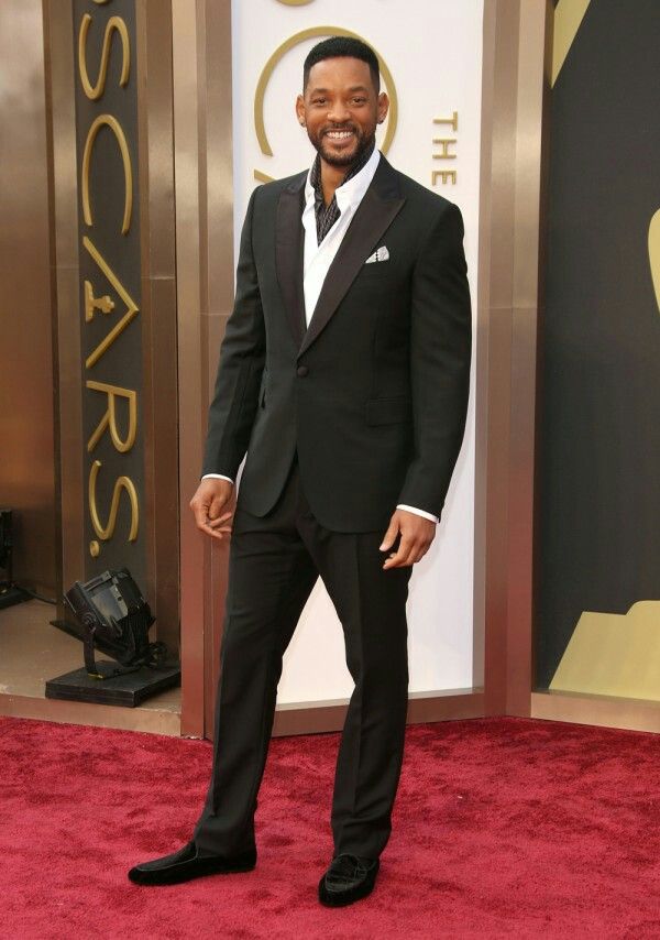 a man in a tuxedo standing on a red carpet