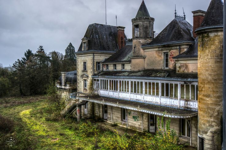 an old building with many windows and towers on it's roof, surrounded by trees