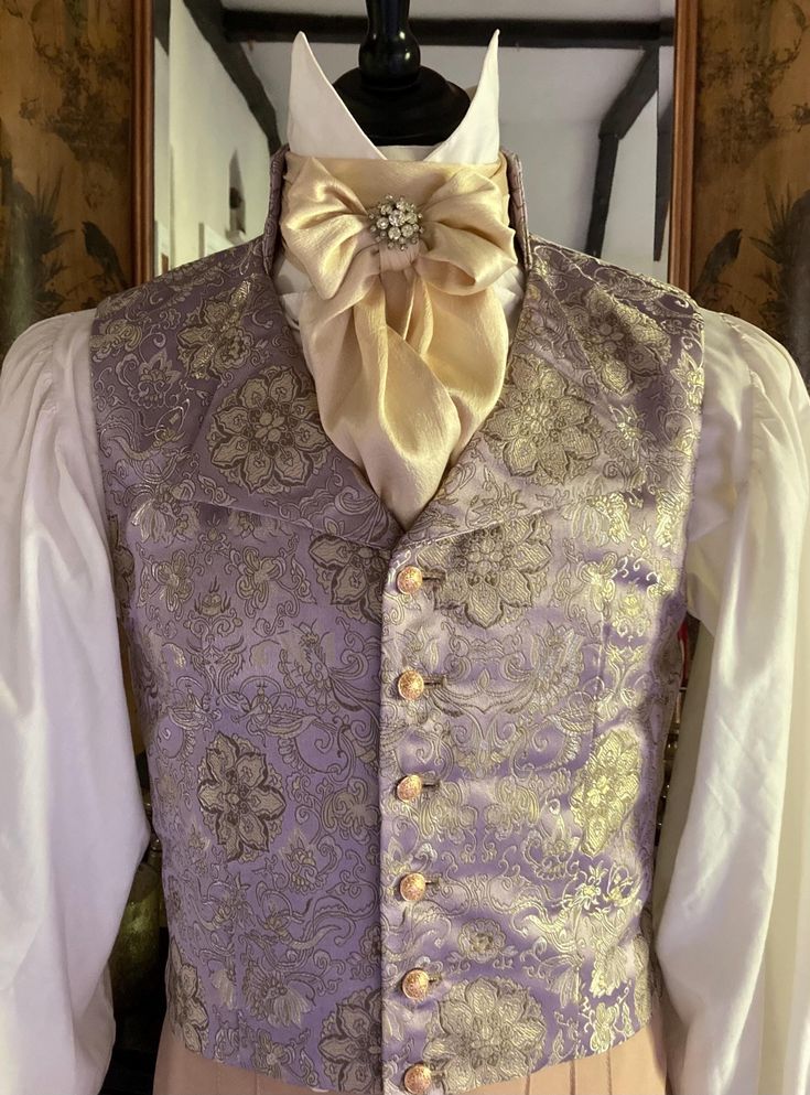 Mens single breasted Regency style waistcoat made in an opulent lilac, gold and silver brocade in an eye catching floral design, six gold tone filigree buttons, stand collar with shaped lapels. The sumptuous fabric is a lavish lilac, gold and silver brocade in an eye catching floral design, the metallic threads catch the light wonderfully, the fabric is absolutely perfect for the Regency period. It will look stunning for a Regency Ball, Bridgerton Event, Regency Wedding, The Jane Austen Festival Elegant Party Vest With Buttons, Elegant Wedding Vest With Buttons, Sleeveless Vest With Buttons For Wedding, Fitted Wedding Vest With Buttons, Fitted Vest With Buttons For Wedding, Fitted Gold Vest Elegant Style, Elegant Gold Fitted Vest, Gold Fitted Vest, Fitted Gold Elegant Vest