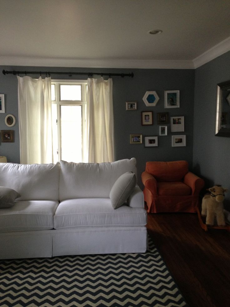 a living room filled with furniture and framed pictures on the wall above it's windows