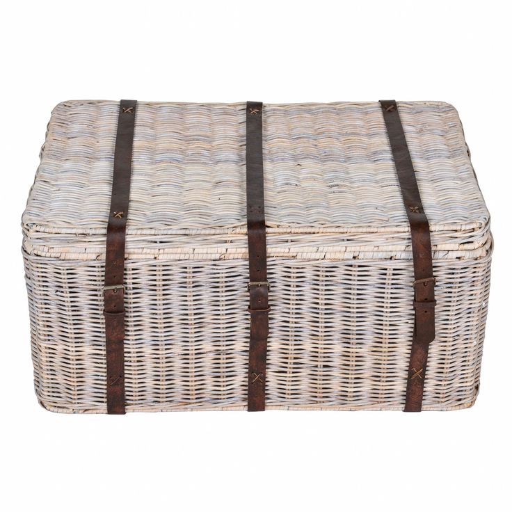 a wicker trunk with leather straps on the bottom and sides, sitting against a white background