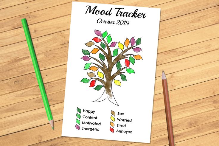 a notepad with a colorful tree on it next to pencils and a green marker