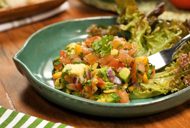 a salad with lettuce, tomatoes and other vegetables in a bowl on a table