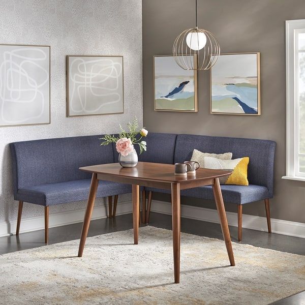 a corner table with two benches in front of it and paintings on the wall behind it