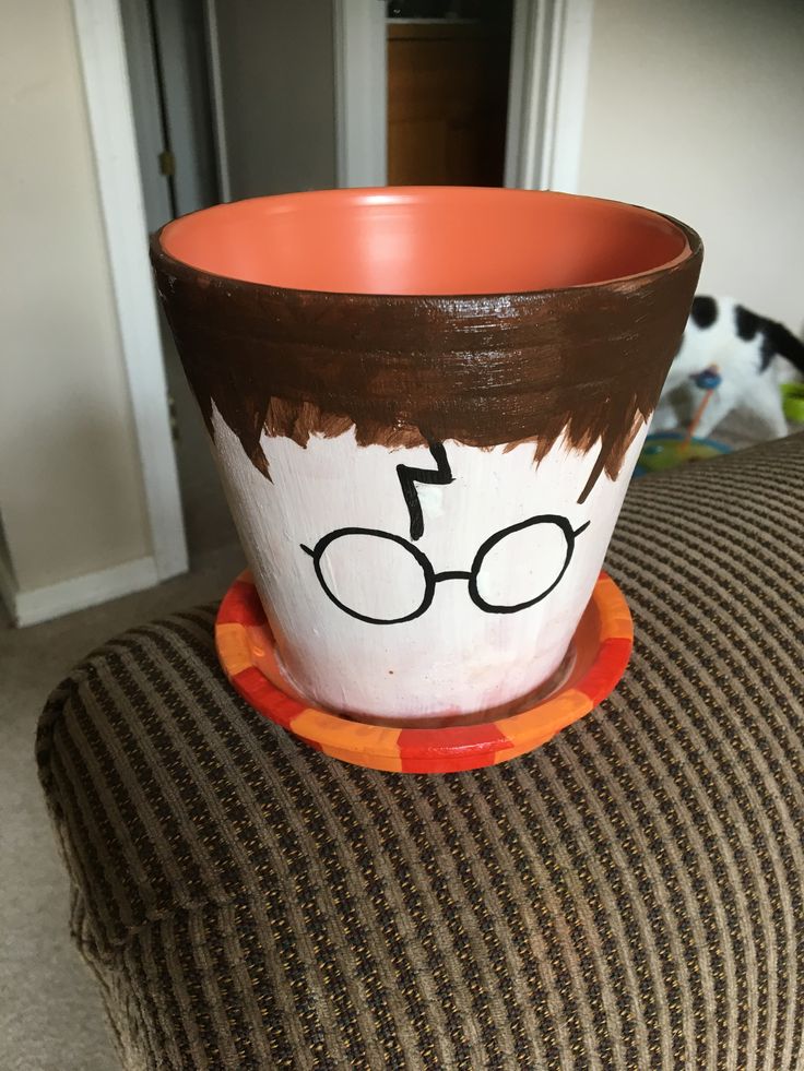 a coffee cup with glasses painted on it sitting on a chair next to a cat