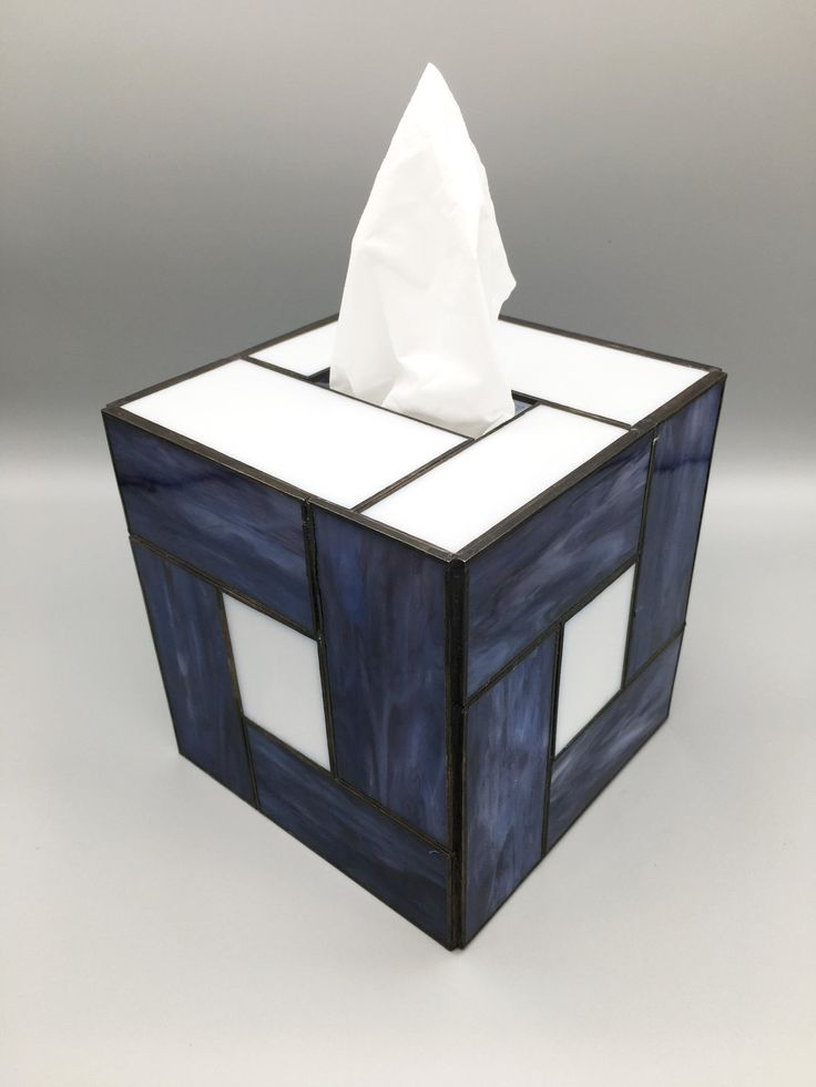 a tissue dispenser that is made out of stained glass and has white paper on top