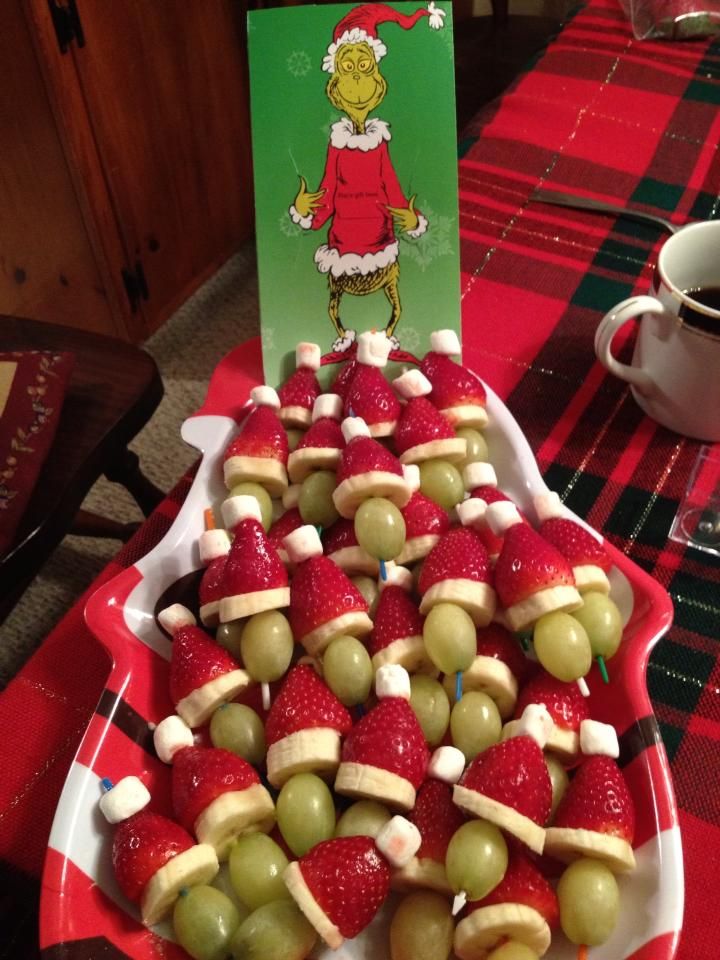 a tray filled with apples and grapes on top of a red tablecloth covered table