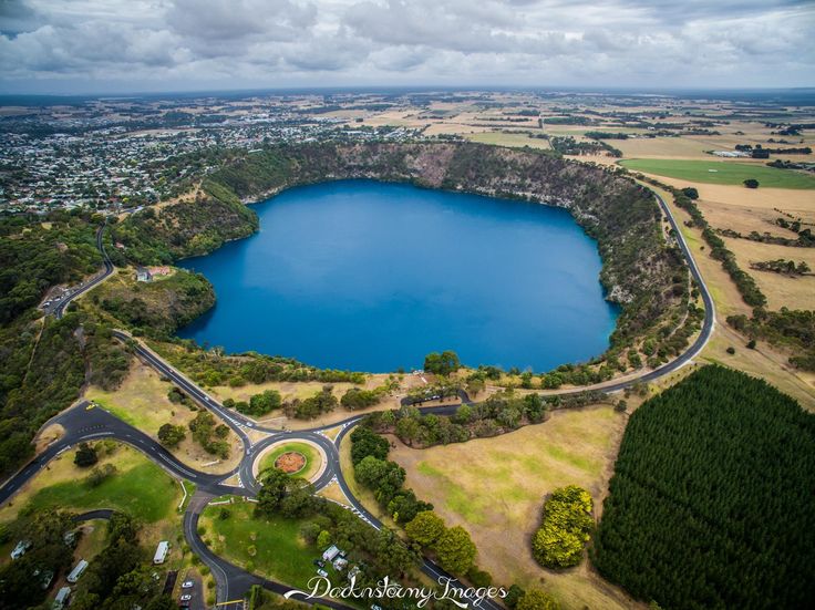 an aerial view of a large blue lake surrounded by green fields and trees in the foreground