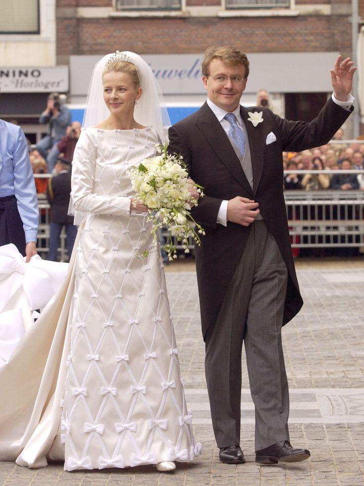 the bride and groom are walking down the street with their hands in the air as they wave