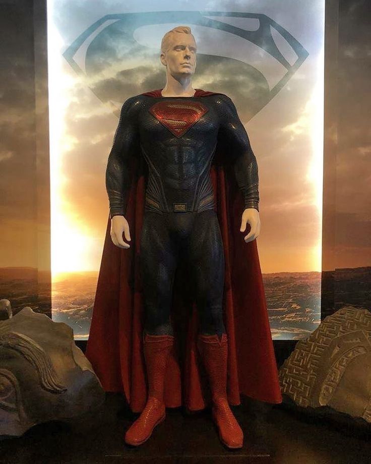 a statue of superman stands in front of a poster