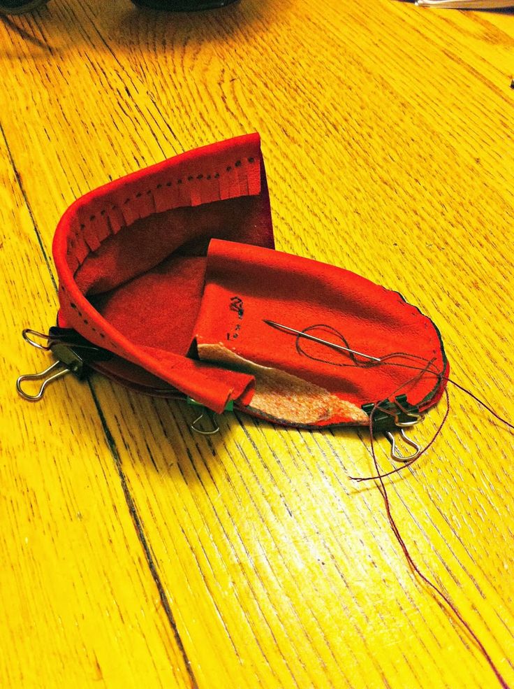 a red boat sitting on top of a wooden table next to a pair of scissors