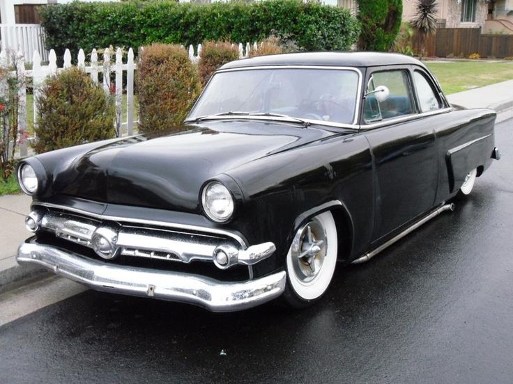 an old black car is parked on the street