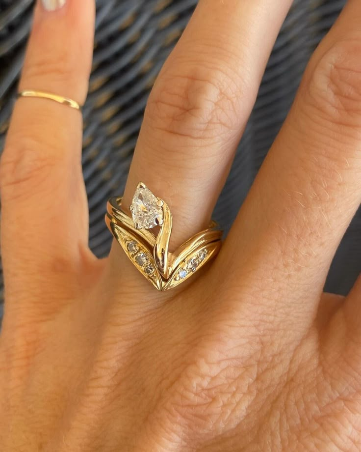 a woman's hand with two gold rings on top of her finger and the ring has three diamonds in it