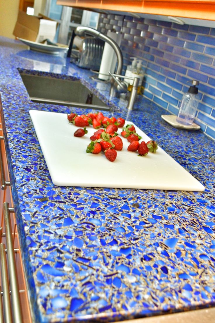 strawberries on a cutting board in the middle of a kitchen counter top with blue tiles