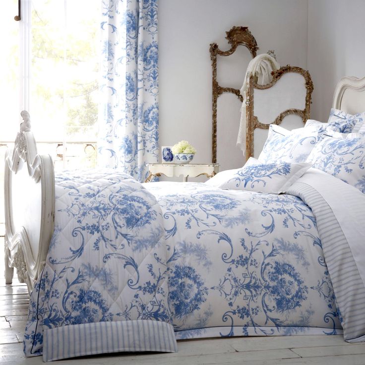 a bed with blue and white comforters in a bedroom next to a window,