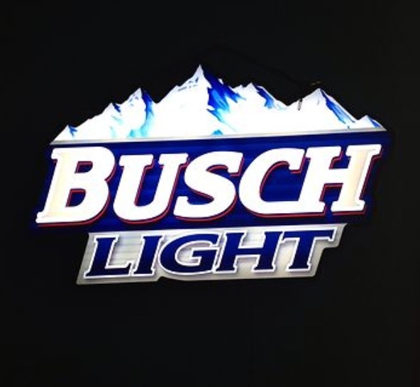 the busch light logo is lit up in the dark with snow capped mountains behind it