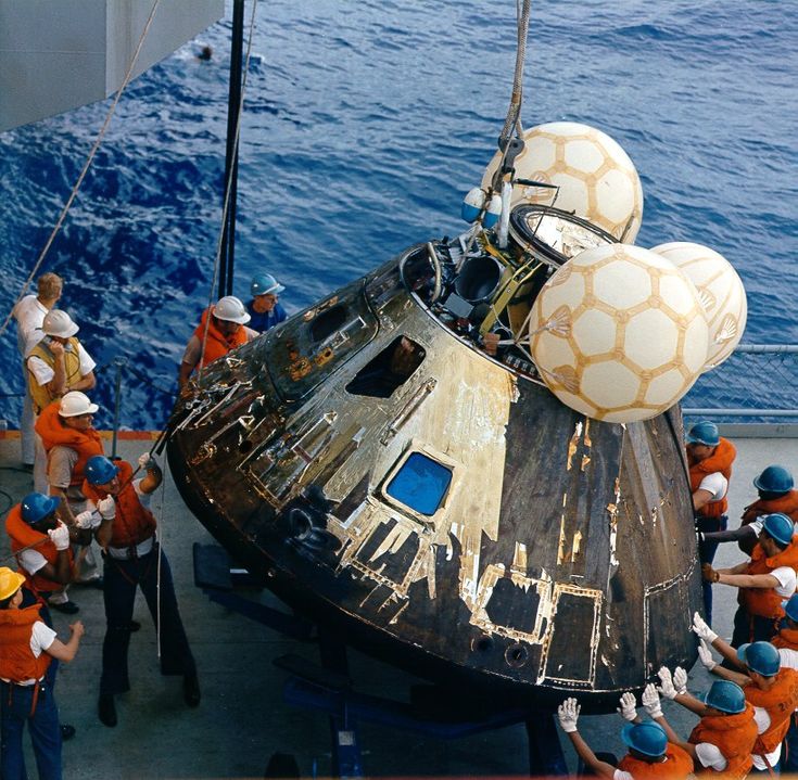 several people are standing on the deck of a ship near an object in the water