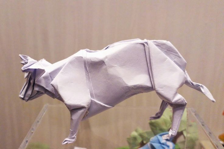 an origami cow on display in a glass case