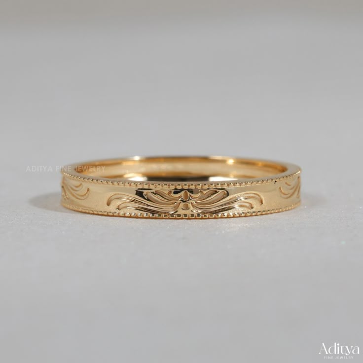 a gold wedding band with an intricate design